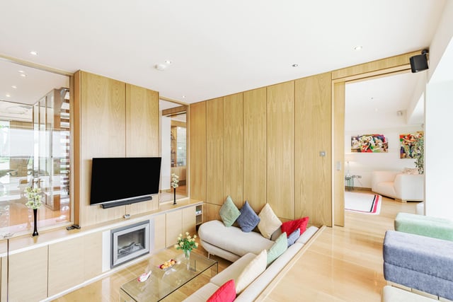 One of the most striking features is the family room, with a bespoke sunken seating area with acoustic wooden wall panels and views over the garden and beyond. Further double doors lead to a formal sitting room with wall mounted speakers, a bespoke fitted illuminated drinks cabinet and floor to ceiling windows overlooking the garden.
