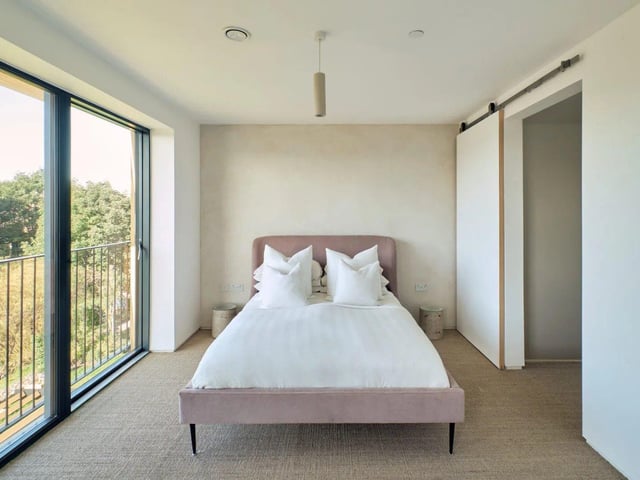 A birch-faced plywood staircase rises to the first floor, where a small landing leads to a river-facing bedroom with generous storage.