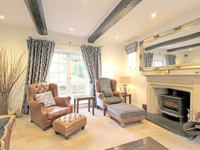 A living room with feature fireplace and stove, and French doors leading outside.