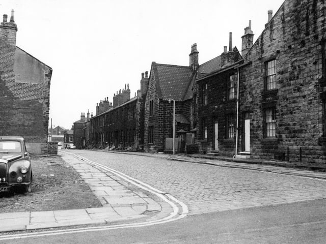 A view looking along Oddfellow Street from the junction with Wesley Street towards Fountain Street in August 1968. A block of terraced houses have been demolished on the left and a car is parked in the waste ground.