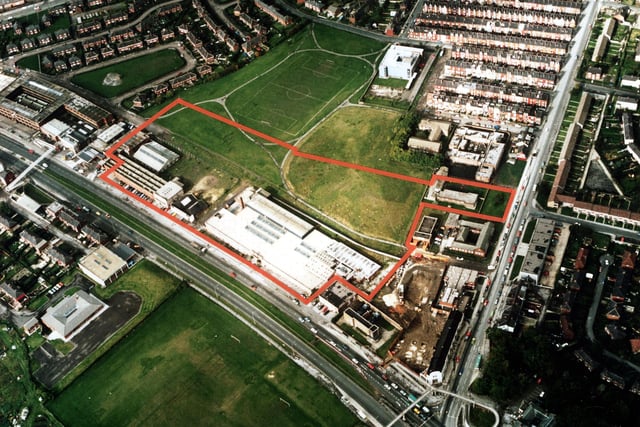 A colour aerial view showing York Road, with Harehills Lane on the right. Factories and warehouses are in the centre. In the top left is semi-detached housing of Torre Hill and Torre Crescent, and top right terraced housing of the Nowells; the white building next to these is a telephone exchange. Victoria County Primary School is at the bottom left, with the Shaftesbury public house bottom right. Several playing fields are in view including a football pitch. Pictured in March 1985.
