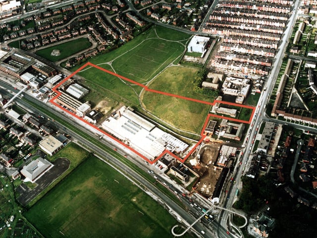 A colour aerial view showing York Road, with Harehills Lane on the right. Factories and warehouses are in the centre. In the top left is semi-detached housing of Torre Hill and Torre Crescent, and top right terraced housing of the Nowells; the white building next to these is a telephone exchange. Victoria County Primary School is at the bottom left, with the Shaftesbury public house bottom right. Several playing fields are in view including a football pitch. Pictured in March 1985.