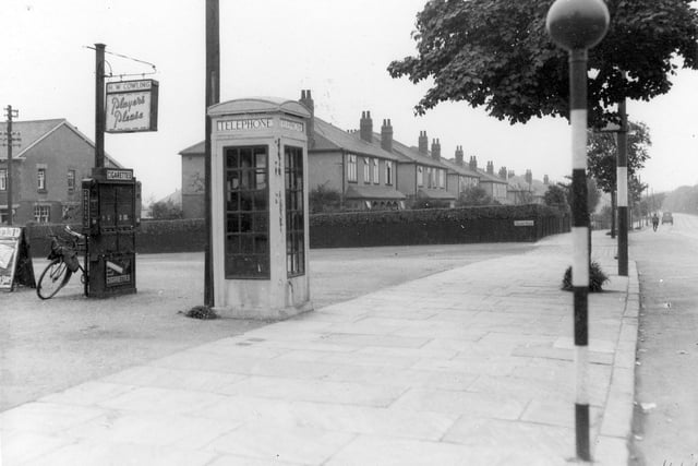 The junction of Street Lane and Talbot Road in June 1936. A telephone kiosk features in the centre of the scene. To the left of this is a cigarette machine and a sign for Harry W Cowling, newsagent. The sign carries an advertisement for Players cigarettes. A Belisha beacon is visible on the roadside.
