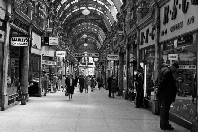 A view looking down the County Arcade from the Briggate end to Vicar Lane in  Shops include Manley's opticians, Cardis Pork butchers, Salisbury's handbags, Walco, RSC Hi Fi centres and Instant shoe repairers. A sign for the Spinning Disc disco is also visible.
