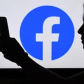 In this photo illustration, a person looks at a smart phone with a Facebook App logo displayed on the background, on August 17, 2021, in Arlington, Virginia. (Photo by OLIVIER DOULIERY / AFP) (Photo by OLIVIER DOULIERY/AFP via Getty Images)
