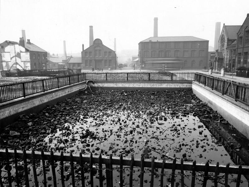 A recently constructed static water supply basin on Ventnor Street pictured in July 1943 full of rubble, perhaps from recent demolition or bombing. The basin is on the site of St Simons Street and J Hinchcliffe Iron Merchants and Hellewell and Son Dyers can be seen on Kirkstall Road. Upton Street has been demolished and the chemist's shop on the end of Townend Street can be seen on the left with Methodist Chapel and Sunday School on the right.