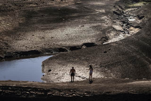 People walking on the exposed earth at Baitings Reservoir in Ripponden, West Yorkshire, where water levels were significantly lower than usual on Friday. Picture: Danny Lawson/PA Wire