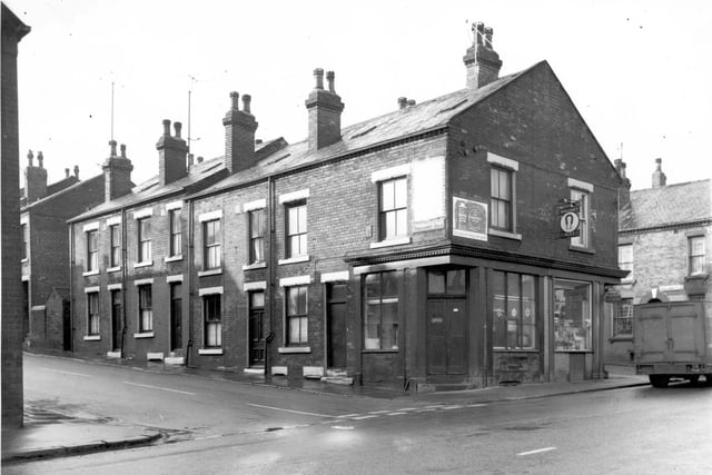 Shops on Parliament Road and Armley Road in February 1968. The shop on the right is an off-licence advertising Magnet Ales and Lyons. In the distance is Parliament Place with a truck belonging to Fred Taylor's Wholesale Provisions.