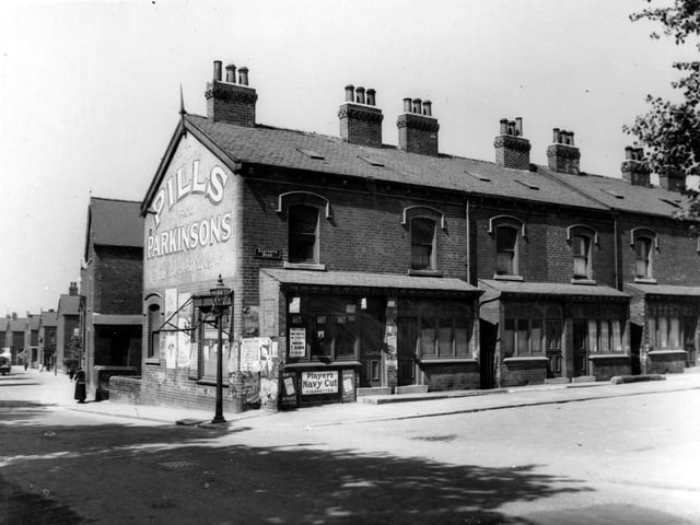 The corner of Seaforth Avenue and Foundry Lane in June 1939 showing a shop with advertisements for Parkinsons Pills, Players Navy Cut, a street lamp, people in the far distance and a woman with a basket. Back-to-back houses.