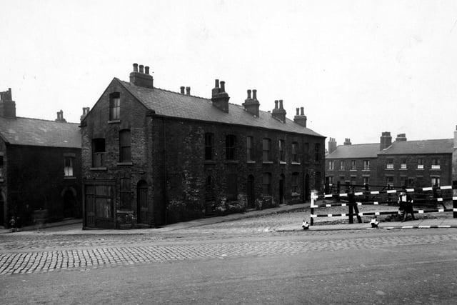 A row of derelict houses on Uhlan Place, off St. Andrews Street. There is a boy leaning against some fencing on the right, which is in front of some workmen's rubble. Two other children are on the left, facing in towards Thiers Place. Pictured in  August 1943.