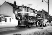 Passengers alighting from tram no.114 at a stop on Stanningley Road in August 1952. The Station Garage is on the left. To the right of the tram is Bramley Home Bakeries at the junction with Hough Lane. Tram no.114 was a Chamberlain which ran in service between November 16, 1926 and February 10, 1955. It is here on route 14 displaying the destination 'Corn Exchange', presumably in readiness for turning round to make the return journey to the city centre.