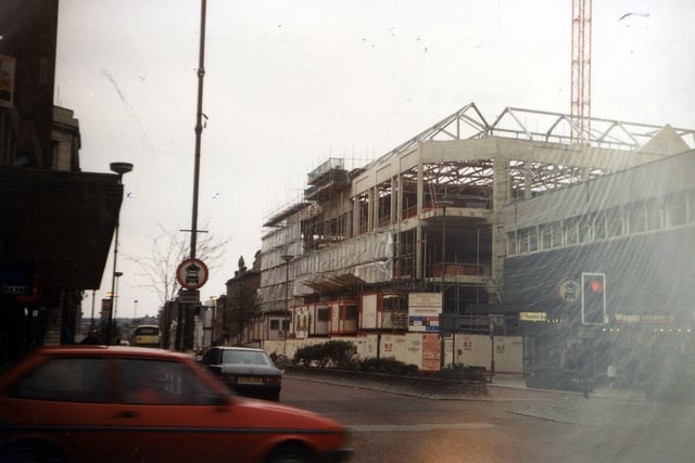 The Headrow from the junction with Albion Street, out of which a car is emerging in the foreground, looking towards the construction of the new Schofields Shopping Centre in  This was built on the site of the old Schofields department store