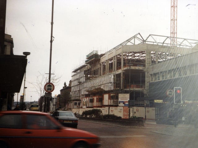 The Headrow from the junction with Albion Street, out of which a car is emerging in the foreground, looking towards the construction of the new Schofields Shopping Centre in  This was built on the site of the old Schofields department store