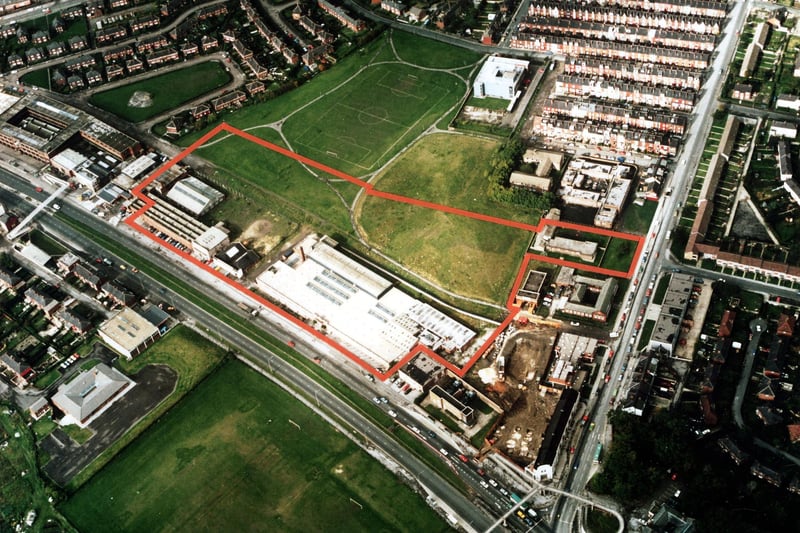 A colour aerial view showing York Road, with Harehills Lane on the right in March 1985. Factories and warehouses are in the centre. In the top left is semi-detached housing of Torre Hill and Torre Crescent, and top right terraced housing of the Nowells; the white building next to these is a telephone exchange. Victoria County Primary School is at the bottom left, with the Shaftesbury public house bottom right. Several playing fields are in view including a football pitch.