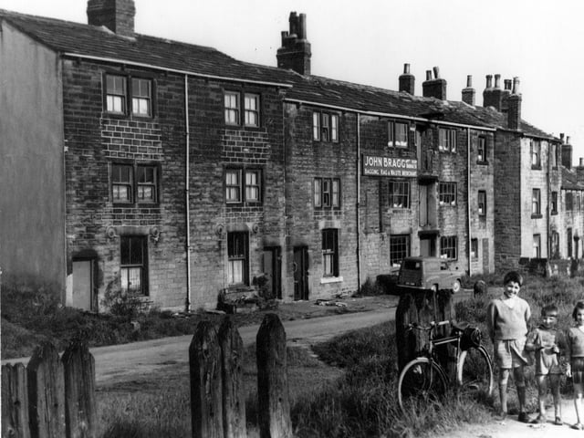 Three children pose for the photograph on Hunger Hill in June 1965. In the centre of the photograph are the premises of John Bragg, bagging, rag and waste merchant.