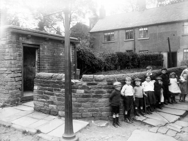 Children stand against low stone wall on corner of properties adjoining the Tower buildings on Woodhouse Cliff in June 1913.