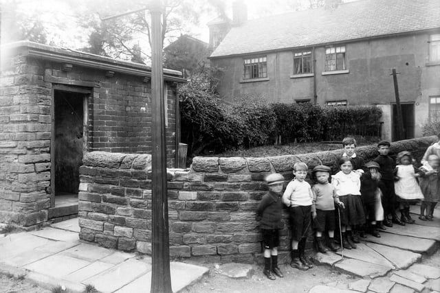 Children stand against low stone wall on corner of properties adjoining the Tower buildings on Woodhouse Cliff in June 1913.
