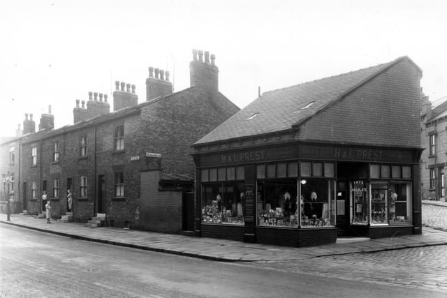 Back-to-back houses on Armley Ridge Road in July 1960. To the right is an outside toilet block and pedestrian access to Wainman Square, then a confectioners on Paisley Terrace. This was the business of Hilda and Lily Prest who were 'High Class' bakers and pastry cooks and offered wedding cakes and party catering.