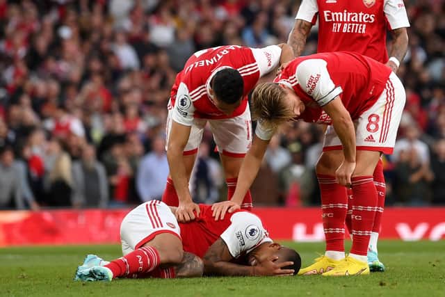 LONDON, ENGLAND - OCTOBER 09: Gabriel Martinelli and Martin Oedegaard tend to Gabriel Jesus of Arsenal as they lie on the floor after taking a knock during the Premier League match between Arsenal FC and Liverpool FC at Emirates Stadium on October 09, 2022 in London, England. (Photo by Shaun Botterill/Getty Images)