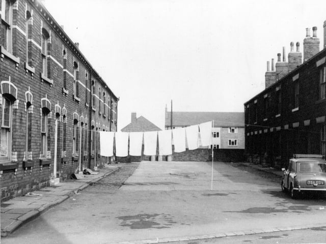 Terraced houses on Commercial Square off Commercial Street with a line of washing across. A mini is parked to the right of the Square. Pictured in April 1967.