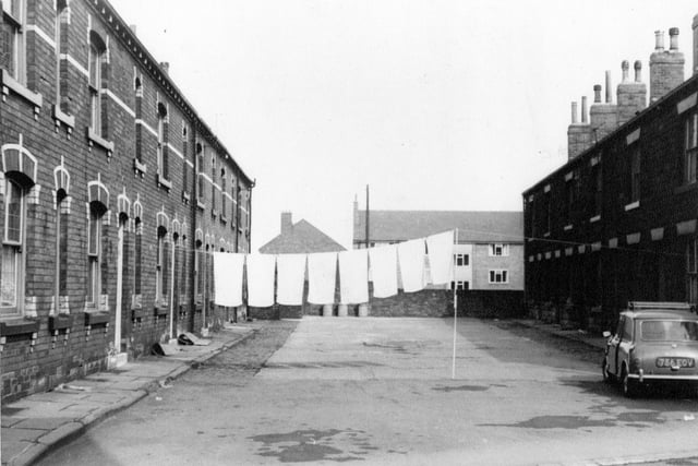 Terraced houses on Commercial Square off Commercial Street with a line of washing across. A mini is parked to the right of the Square. Pictured in April 1967.