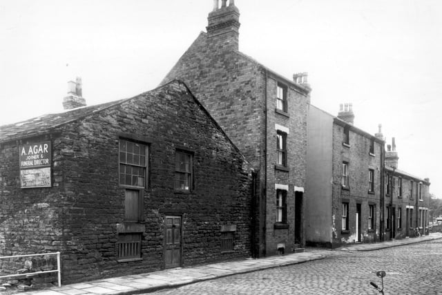 View along Dairy Street looking from the corner with Delph Lane. On the left is the premises of Arthur Agar, joiner and funeral director. The side is onto Holroyds Yard. The house standing to the right of Agar's is number 7 Dairy Street. Pictured in September 1959.