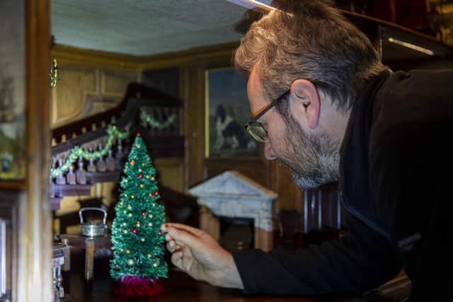 Trust property curator Simon McCormack dressing the dolls' house for Christmas