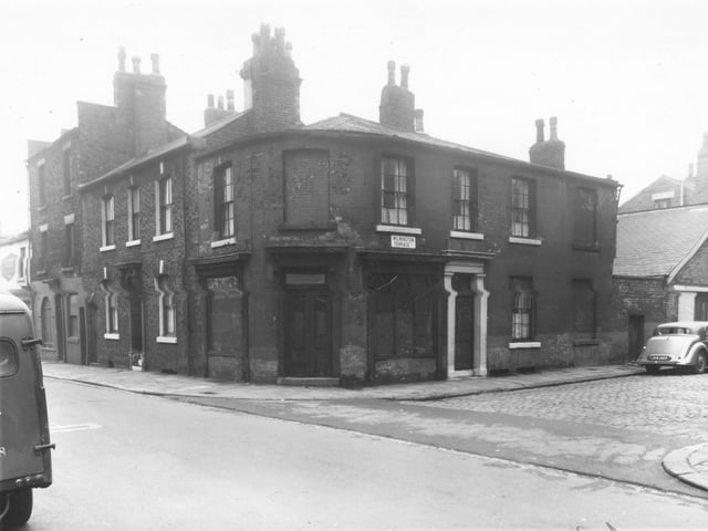 At the left edge is a shop facing onto Meanwood Road at number 62, John Jones greengrocer. Moving right is Barrack Street, number 9 is at a corner with Wilmington Terrace. This former furniture shop is boarded up, on the right is 1 Wilmington Terrace then yard area behind Meanwood Road shops. Pictured in October 1960.