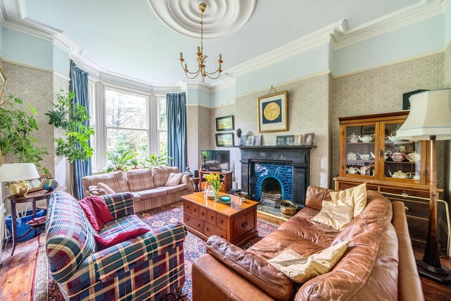 The living room features an open fireplace set within an original surround and a bay window.
