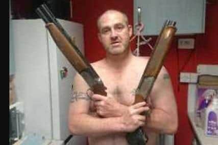 Hoban posing with the guns found at his home.