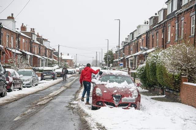 A commuter clears his car in Beeston after heavy snow overnight