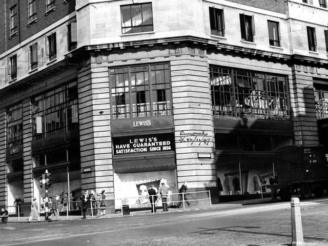 Shows Lewis's department store on the corner of The Headrow and New Briggate in August 1947. 'Satisfaction Guaranteed' signs outside.