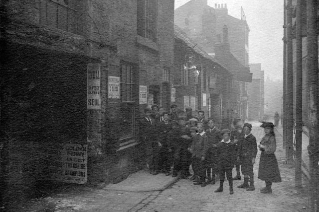 Property on Lands Lane in September 1898 prior to improvement. Notices on wall give details of company removal. Large number of children in Period dress. The Lands referred to in the street name were the fields belonging to the Lord of the Manor of Leeds.