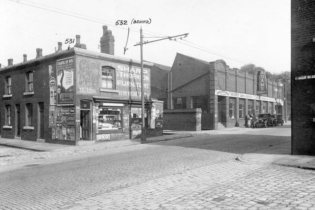Stoney Rock Lane showing side streets Rock Terrace and Fraser road. On the right is Adams Motor Sales and Service with two men and two cars in the road. On the left is a general store at the end of Rock Terrace. Pictured in September 1935.