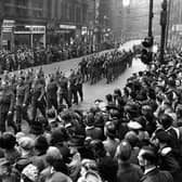 Military parade on Boar Lane, which was part of the route taken which ended at Leeds Town Hall on The Headrow. Unseasonably bad weather had delayed the Normandy Invasion Forces, the D-Day landings took place 3 days later on the 6th of June. Many of the people seen here in the crowd are wearing coats and hats, prepared for rain.