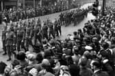 Military parade on Boar Lane, which was part of the route taken which ended at Leeds Town Hall on The Headrow. Unseasonably bad weather had delayed the Normandy Invasion Forces, the D-Day landings took place 3 days later on the 6th of June. Many of the people seen here in the crowd are wearing coats and hats, prepared for rain.