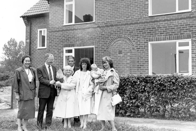 Councillor George Mudie as he presents keys to new tenants of Brander Mount. This was the conversion of 12 'cottage' style flats to 6 2-bedroomed semi-detached homes, carried out under the Priority Estates Programme and the Community Refurbishment Scheme. It was part of a long-term plan by Leeds City Council to improve the standard of older housing estates in the city. The houses were equipped with new bathrooms, central heating, new roofing, re-wiring and new doors and windows at a cost of £20,000 each. The new tenants pictured are Geoff, and Brenda Bull with Mrs. Bull's mother, Mrs. Lizzie Speight and Jane Green with her nine month old daughter, Rachel.