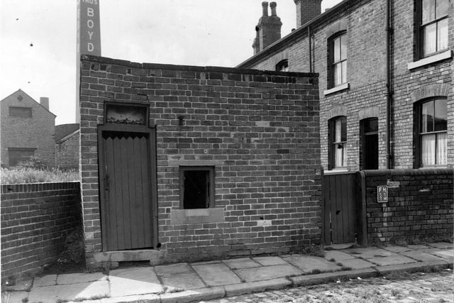 Toilets at the back of a terraced house on Sowerby Street. Thomas Boyd Mills in the background. Pictured in July 1953.