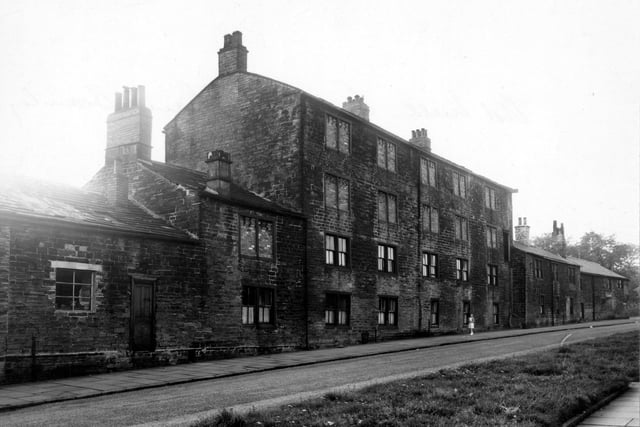 A girl stands in front. of old cottages on Eightlands Lane in August 1956. These were numbered as Town End Yard which was at the other side. The cottages are built of stone and the upper windows are bricked up.