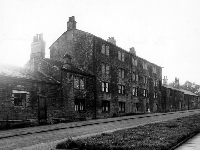 A girl stands in front. of old cottages on Eightlands Lane in August 1956. These were numbered as Town End Yard which was at the other side. The cottages are built of stone and the upper windows are bricked up.