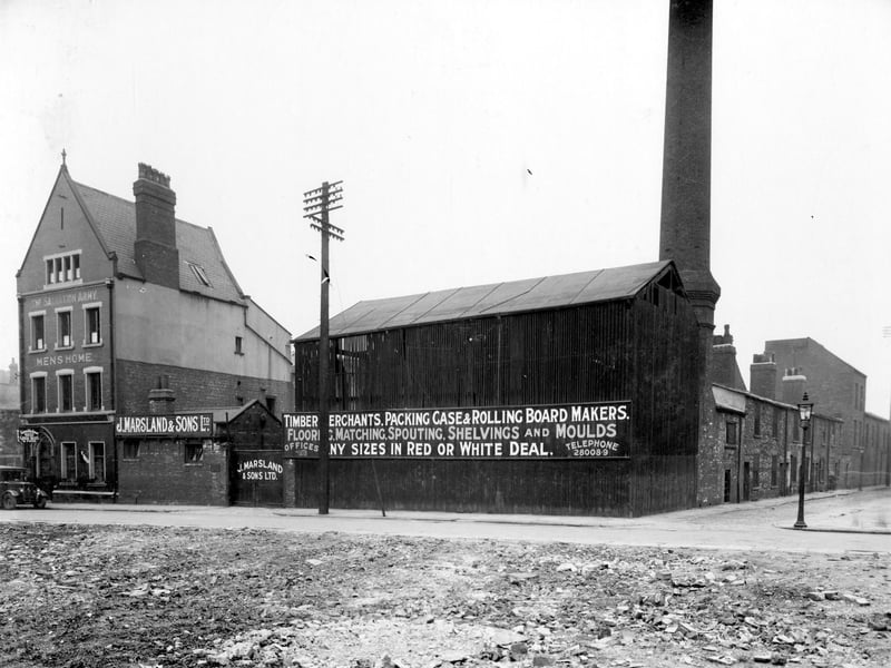 Salvation Army Hostel, painted sign on wall reads 'The Salvation Army Mens Home'. A projecting sign over the doorway states 'The Salvation Army Hostel for Men. Good Beds and Food'. The Salvation Army has a long tradition of working with the homeless. Next, premises of J. Marsland and Sons Ltd., Wellington Street Saw Mills. Sign board reads 'Timber Merchants. Packing Case and Rolling Board Makers, Flooring, Matching, Spouting, Shelving and Moulds'. Junction to right is Skinner Street. Pictured in August 1937.