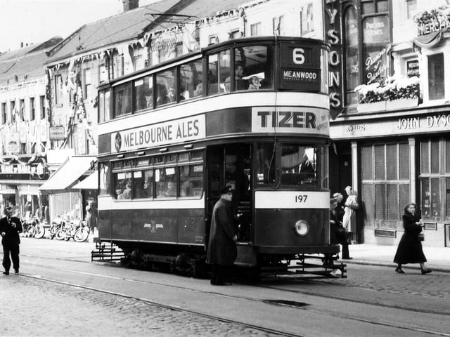 Shops decorated on Lower Briggate to celebrate the coronation. These include Weaver to Wearer tailors and Gaskell & Chambers Ltd., bar fitters, on the left and John Dyson & Sons Ltd., clockmaker and jeweller, on the right. Tram no.197, a 'Horsfield' built 1930-31, is pictured on route 6 to Meanwood.