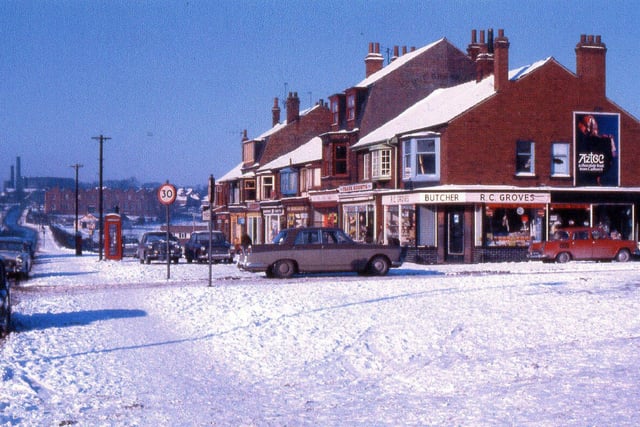 A view looking along Stanningley Road with snow on the ground in February 1969. Wyther Park Mount is in the foreground then the Wyther Park parade of shops with R.C. Groves, butchers, on the corner. The view is looking towards Bramley and Bramley Town End can be seen in the distance on the left.