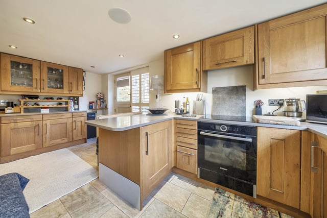 The 'L' shaped kitchen is fitted with modern storage units incorporating a breakfast bar and dining area, with access to the garden.