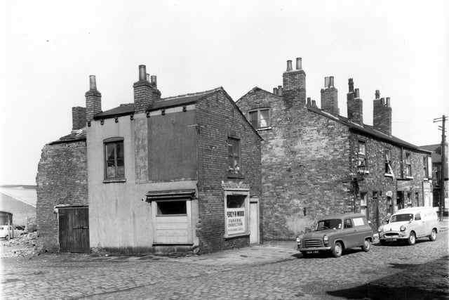 On the left edge of this view the one storey commercial building is part of the yard of Wright and Summerhill Ltd sheet metal engineers, who had an office at 5 Royal Road. Moving right, a partially demolished garage or stable adjoining number 8 Lower Carr Place is visible. A sign suggests that this was once the premises of Percy R. Wood, funeral director, although it appears disused at the present time. Moving right, numbers 3, 2 and then 1 Lower Carr Place can be seen. Number 2 is Clapham's Snack Bar. On the far right edge Balm Road can just be glimpsed. Pictured in April 1959.