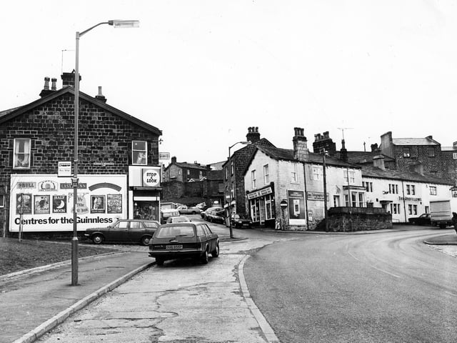 Yeadon's Kirk Lane, foreground, at the junction with The Green, right, and Old Haworth Lane; left. Town Street or 'The Steep' climbs up between the buildings in the centre to the High Street. At number 34 Town Street is Home Electrics. The white building in the centre is a newsagents at the bottom of the steep. In the background, above the parked cars, buildings in Ivegate are visible. The two storey white building, right, is the Odd Fellows Public house or t'rag as it was known locally. It has been renamed The Rag and Louse in recent years.