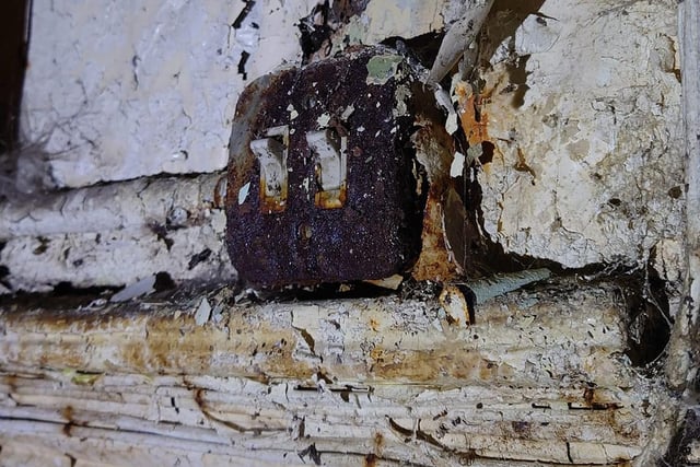 This light switch is barely visible under all the peeling paint