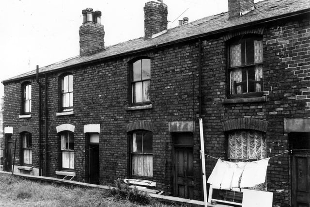 The rear of terraced buildings facing onto Waterloo Road. Clothes are hung out on lines extending from the rear of the houses. The grassed area in the foreground belongs to St. Josephs Catholic Club. Pictured in August 1963.