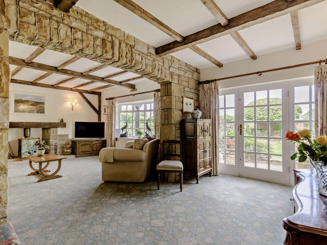 A character lounge with versatile room space has a bay window, exposed stone walls, and a fireplace with woodburning stove.
