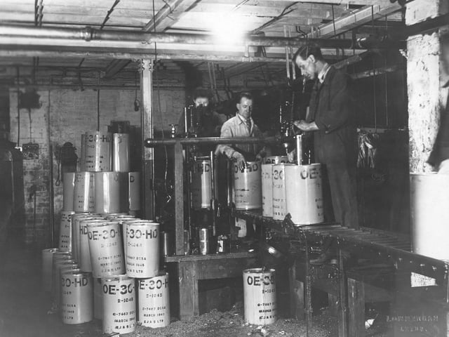 Edward Joy and Sons, filtrate works on Lidacre Street in March 1945. This shows two automotive filling machines working to fill oil drums. The man on the right is using a machine to insert a oil proof inner seal as an additional protection to the cap, for the prevention of oil spillage.